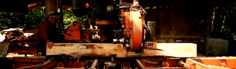 Man turning raw logs into lumber in backyard sawmill